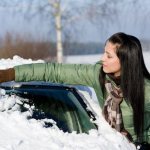 Женщина убирает снег с машины